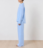 Side view of woman wearing azure linen co-ord set with relaxed button-down shirt and wide-leg trousers