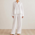Woman wearing a white linen co-ord set with button-down shirt and wide-leg trousers, front view