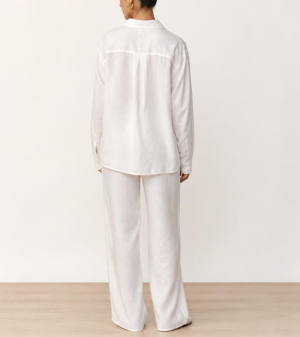 Back view of woman's white linen co-ord set showing collared button-down shirt and wide-leg trousers