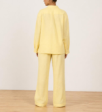 Back view of woman's butter yellow linen co-ord set showing button-down shirt and wide-leg trousers