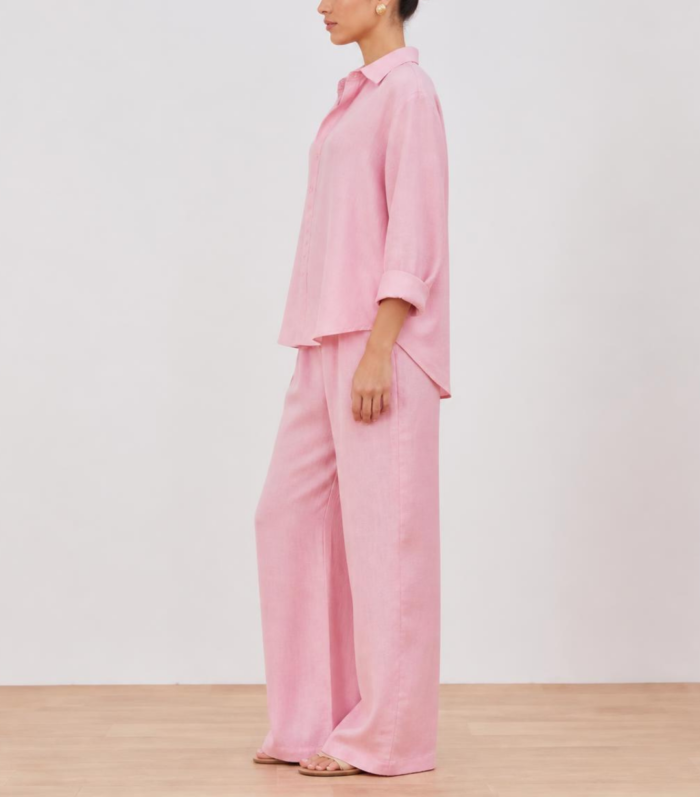 Side view of woman wearing pink linen co-ord set with wide-leg trousers and flat sandals